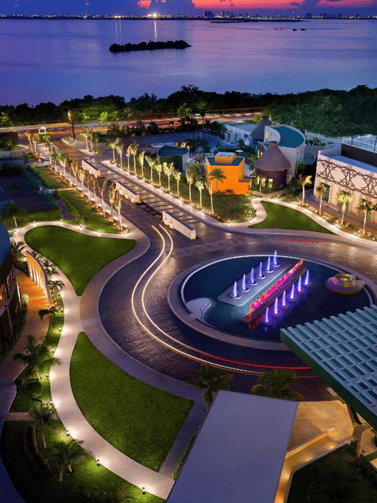 Aerial view of QuestForDirections resort with illuminated fountains and lush landscaping at dusk.