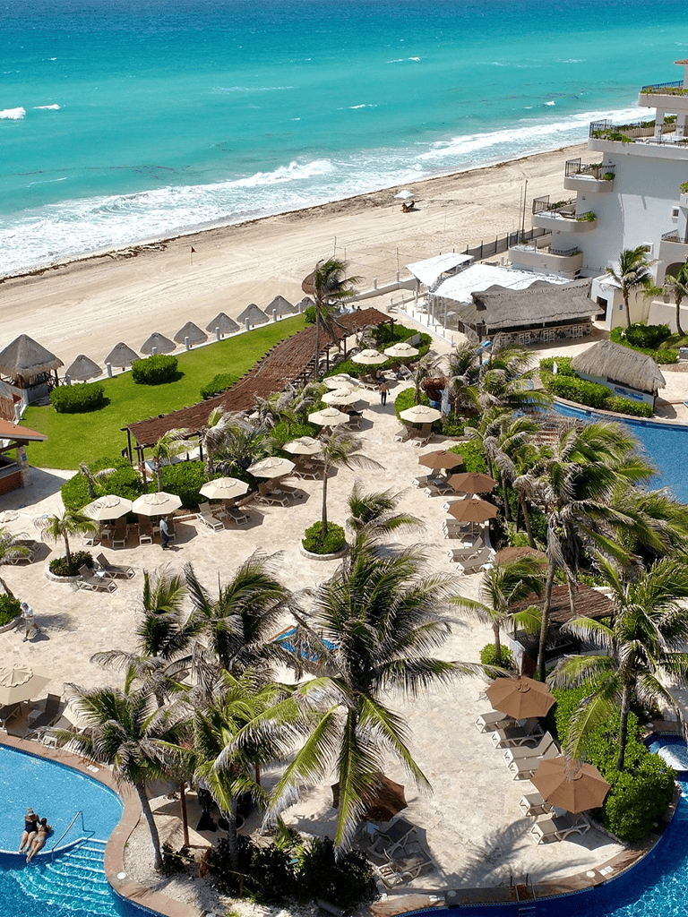 Relaxing beachside resort in Mexico with pool, umbrellas, and ocean view.