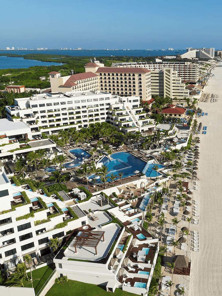 Luxury beachfront resort with pools, palm trees, and ocean view - perfect for vacation stay.