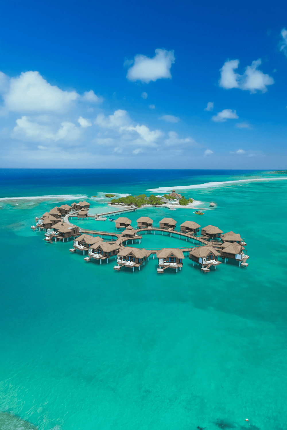 Overwater bungalows in turquoise ocean at tropical island resort, luxury travel, overwater villa vacation, QuestForDirections.