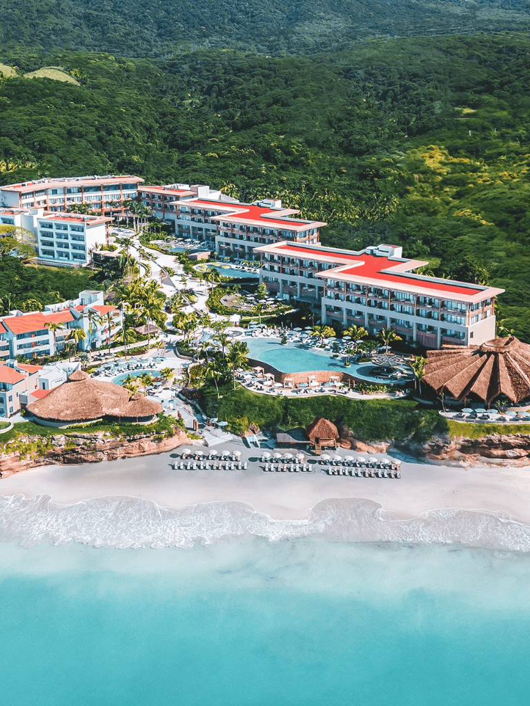 Luxurious beachfront resort with pools and lush green landscape.