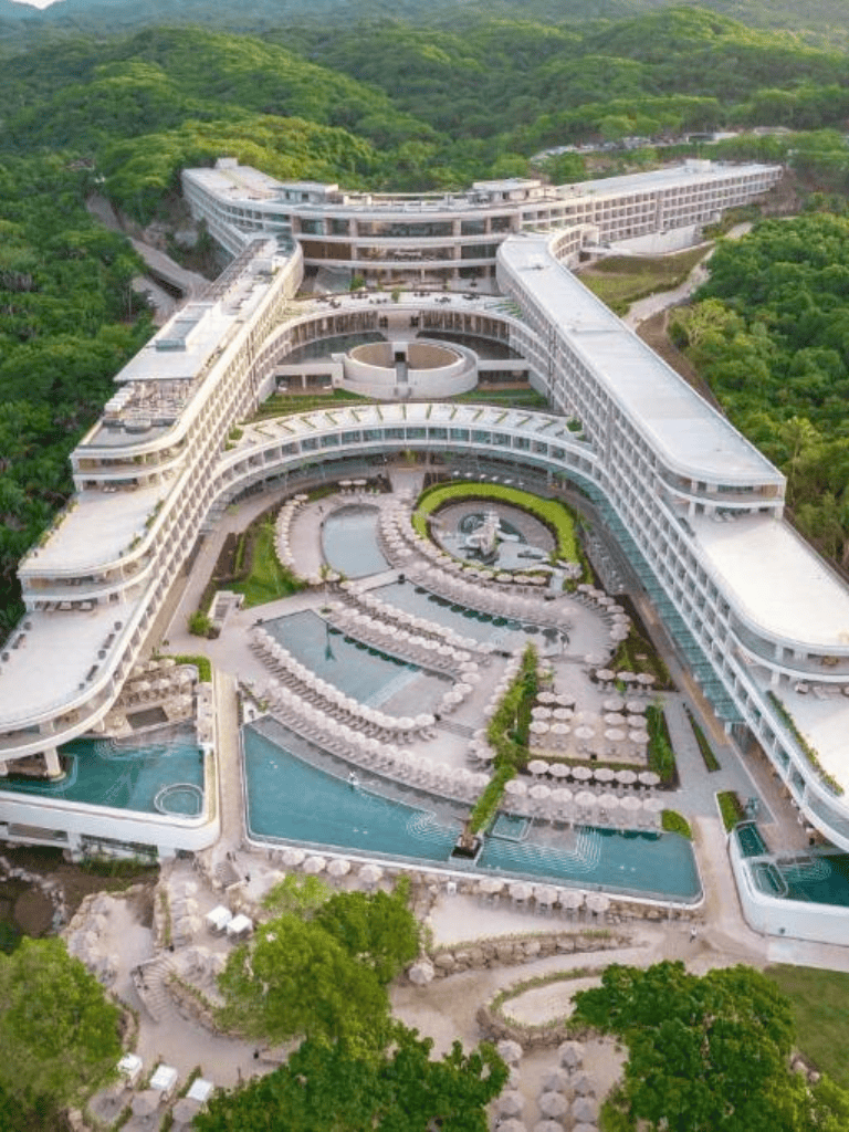 Luxurious hotel with infinity pools near lush green mountains, perfect for relaxation and scenic views.