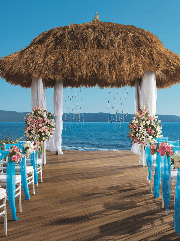 Beachside wedding ceremony setup with floral decorations and ocean backdrop, perfect for destination weddings.