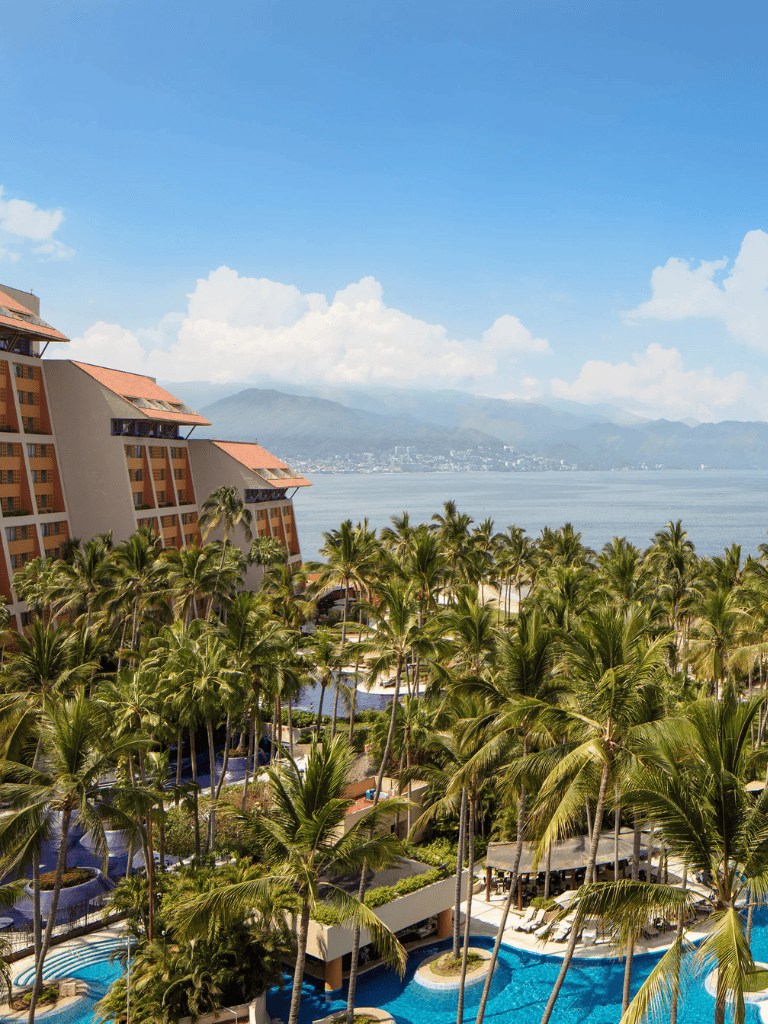 Luxurious resort with palm trees, pool, and ocean view in a tropical destination.