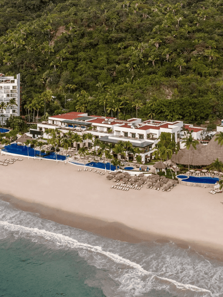 Luxurious beach resort with pools, palm trees, and ocean views in a tropical setting.