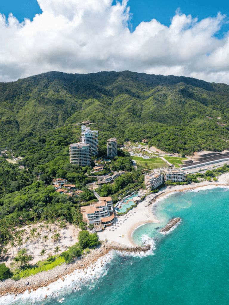 Luxury coastal resort with beach, mountains, and ocean views in a tropical setting.