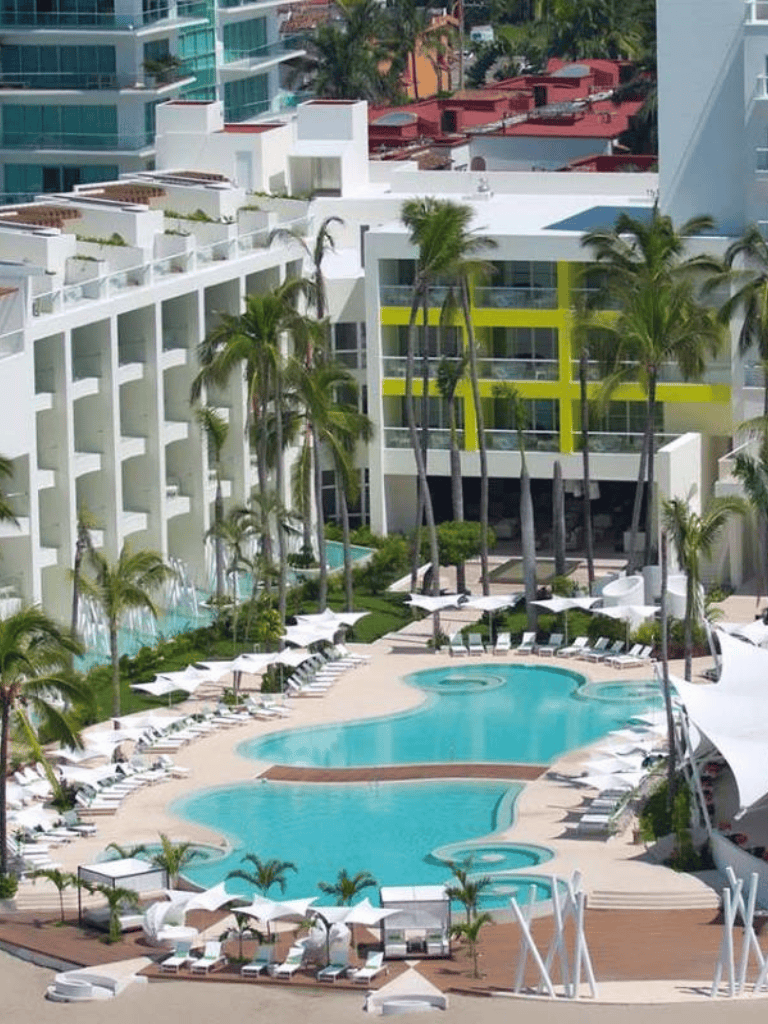 Modern luxury hotel with an infinity pool and palm trees in a tropical urban setting.