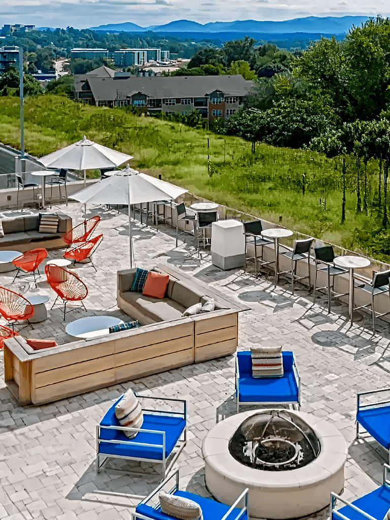 Bright outdoor lounge area with comfortable seating, umbrellas, and scenic green views for relaxation and social gatherings.