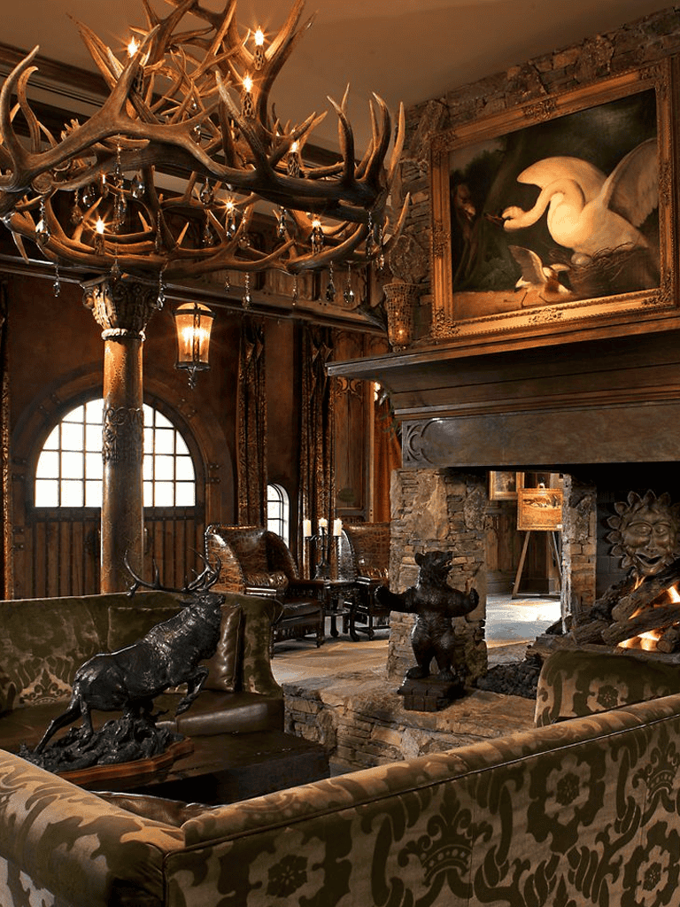 Antler chandelier rustic lodge decor with bear sculptures in cozy mountain living room.