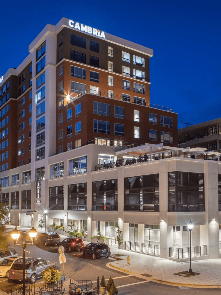 Modern downtown hotel building at night with illuminated signage and city street view.