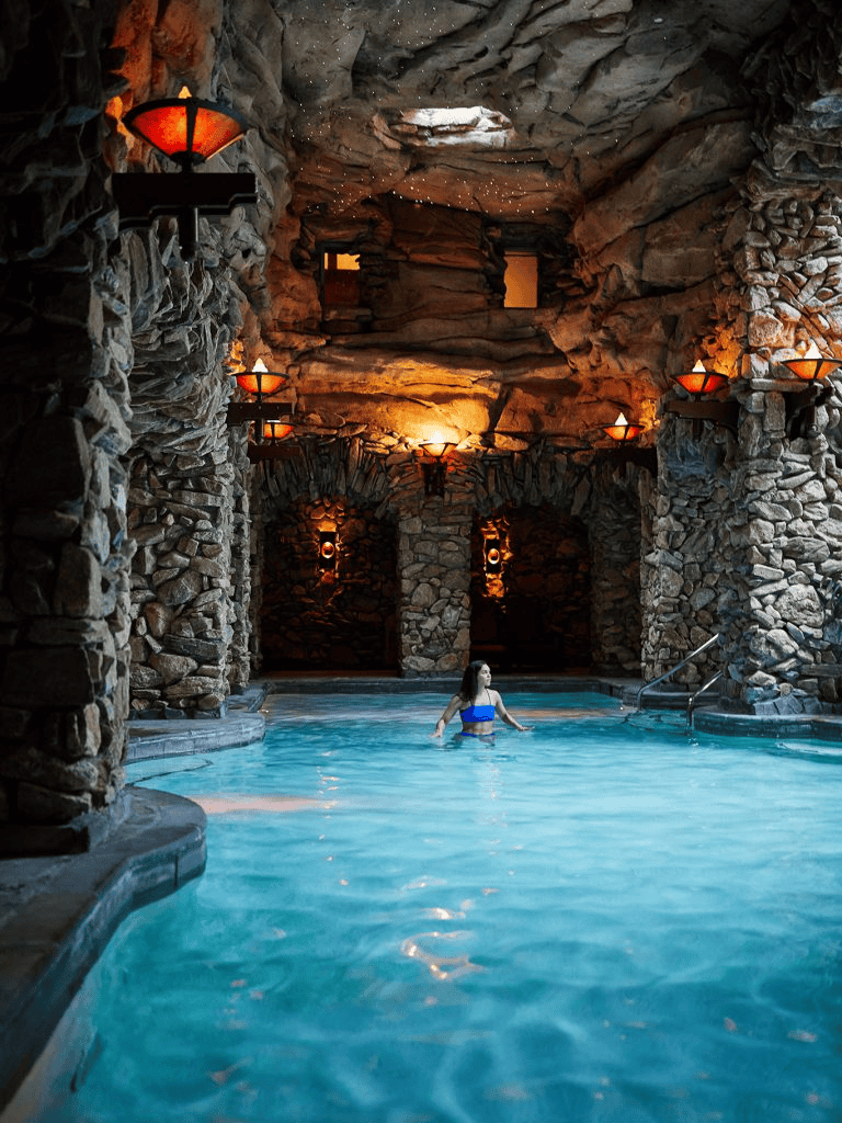 Indoor luxurious stone cave spa with warm lighting and a relaxing pool, perfect for wellness and relaxation.