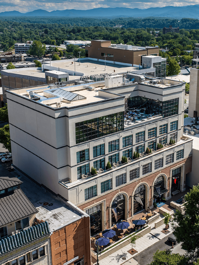 Modern commercial building with rooftop and outdoor patio space in a scenic urban area.