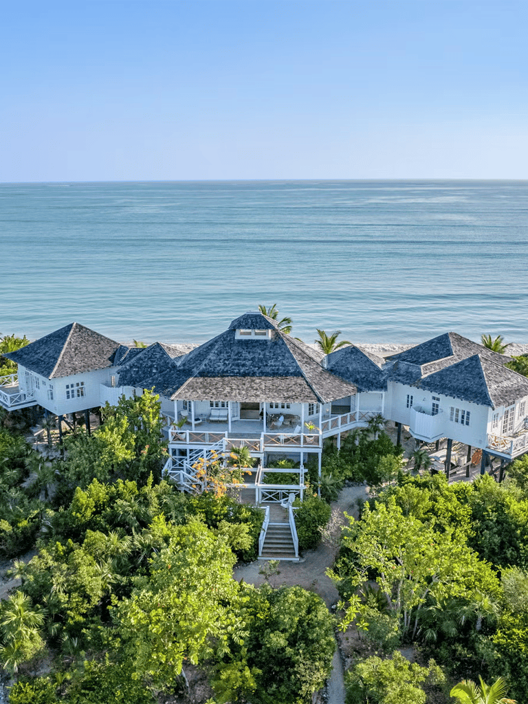 Seafront luxury vacation home with lush greenery at the beach.