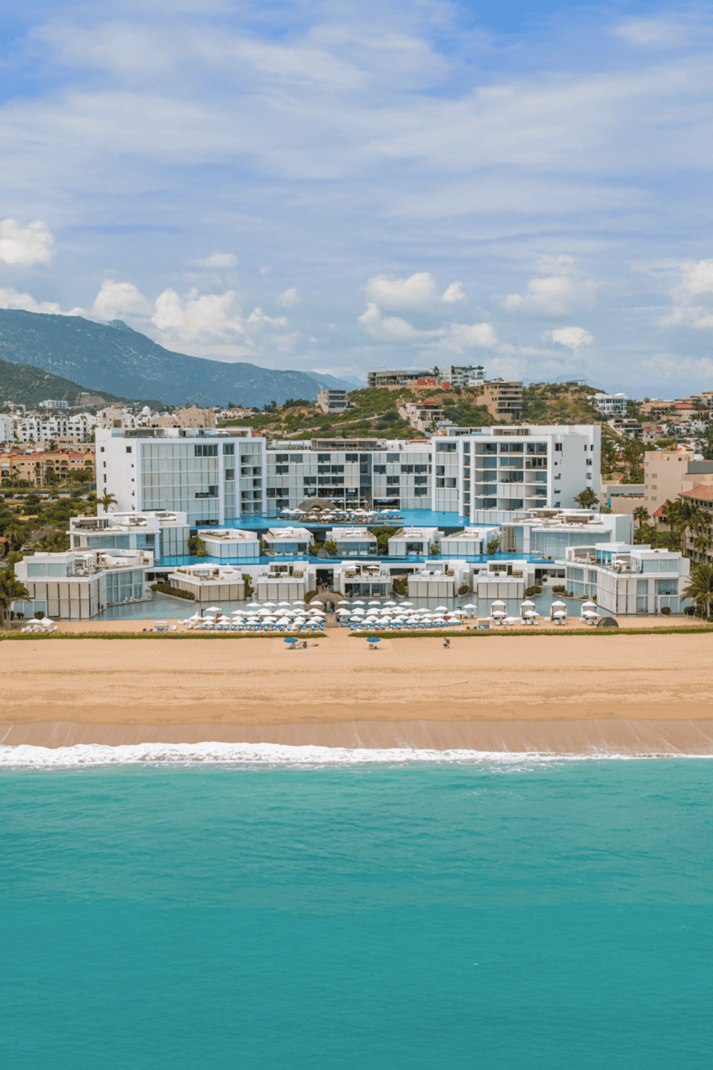 Luxurious beachfront hotel with pool and ocean views in a scenic coastal location.