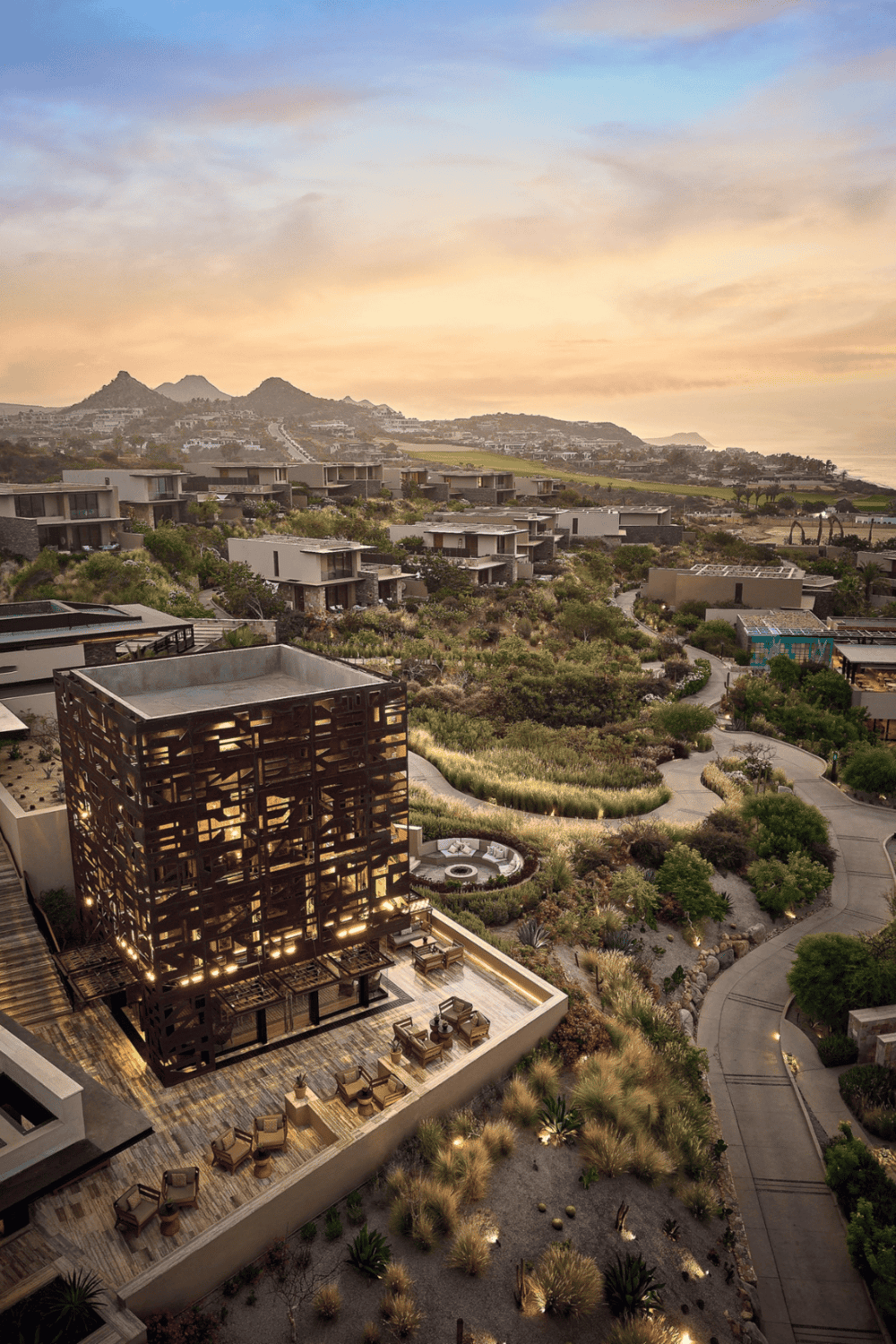 Modern hillside residential community with scenic landscape views at sunset.
