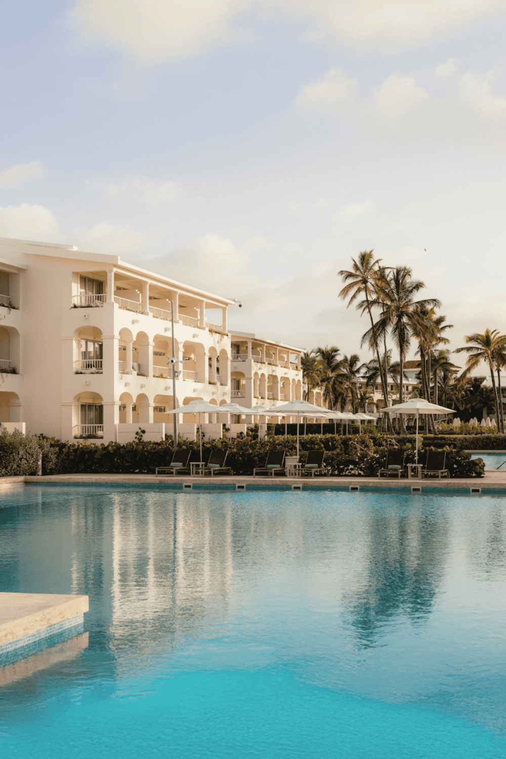 Luxury beachside resort with pool, palm trees, and relaxing atmosphere for vacation travelers.