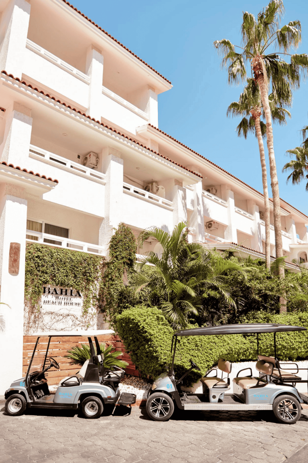 Golf carts parked outside Bahia Hotel Beach House on a sunny day.