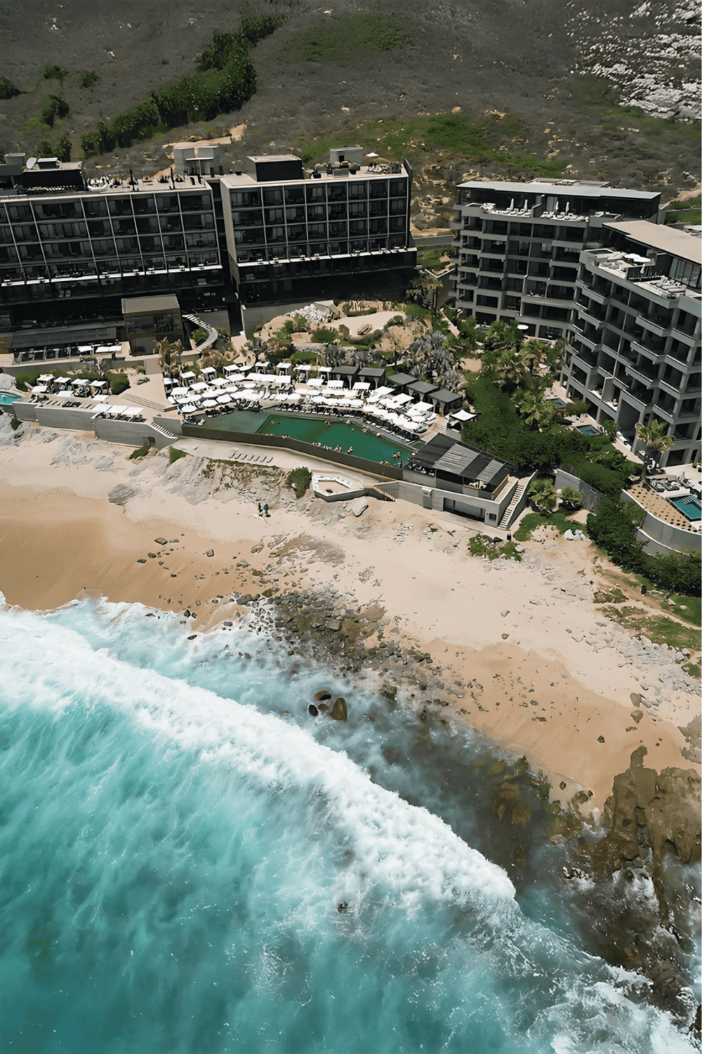 Modern beachfront hotel with pool, overlooking the ocean and sandy beach, perfect for vacation retreats.