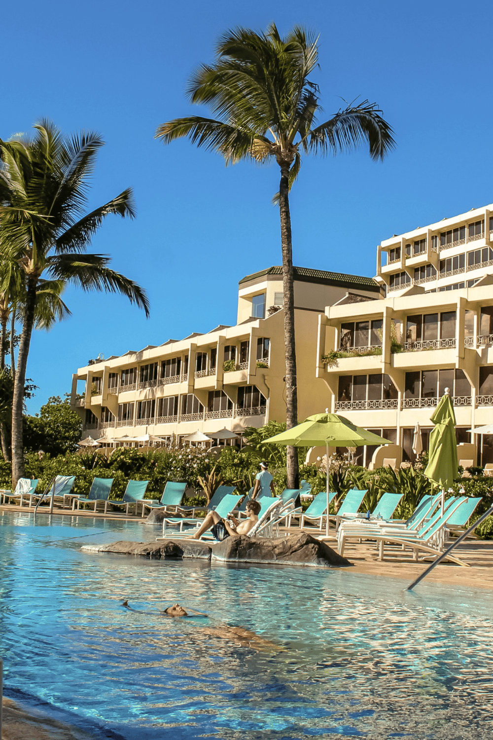 Relaxing resort pool with palm trees and lounge chairs, perfect for vacation and tropical getaways.