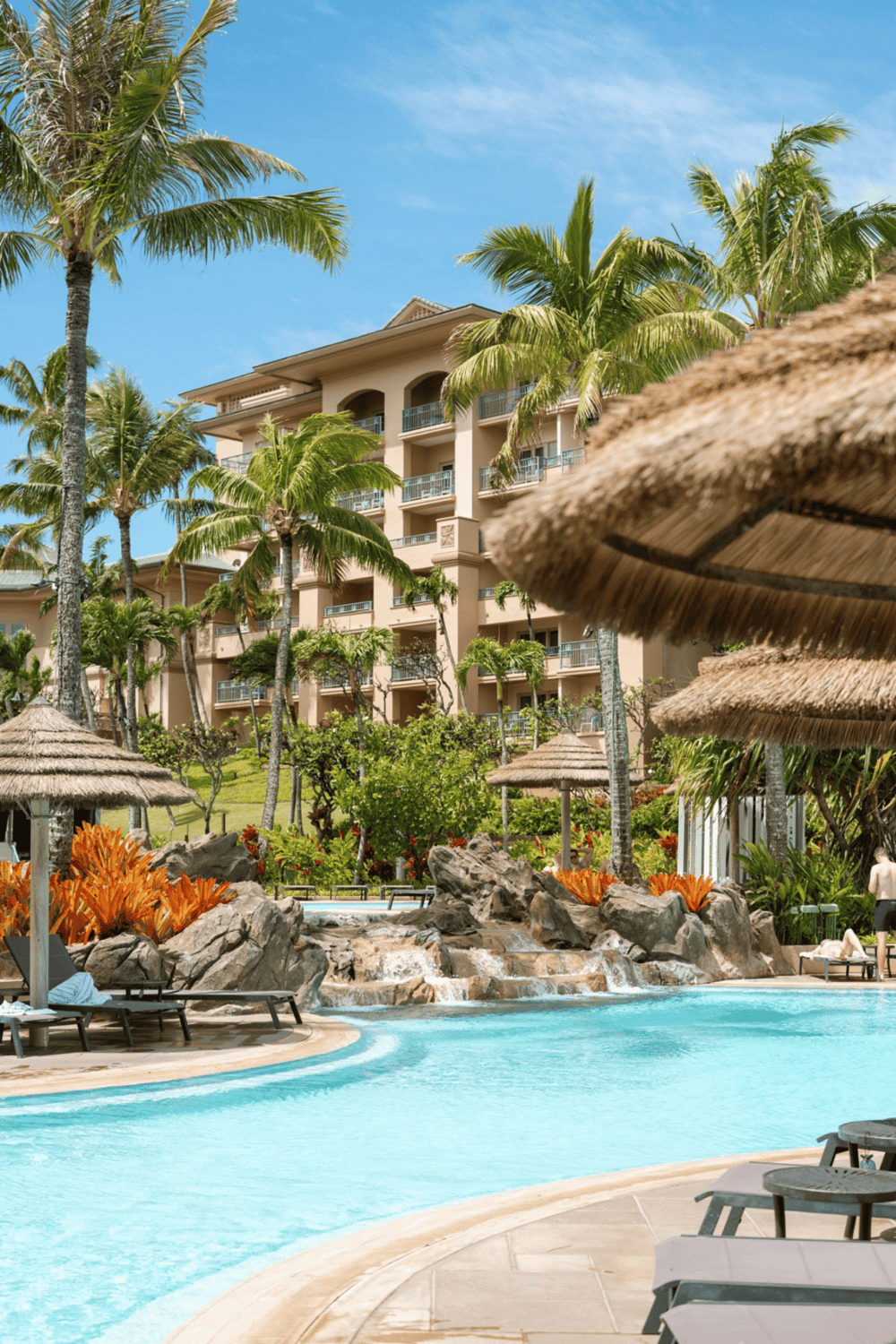 Luxurious tropical resort swimming pool with palm trees and waterfalls, perfect for relaxation.