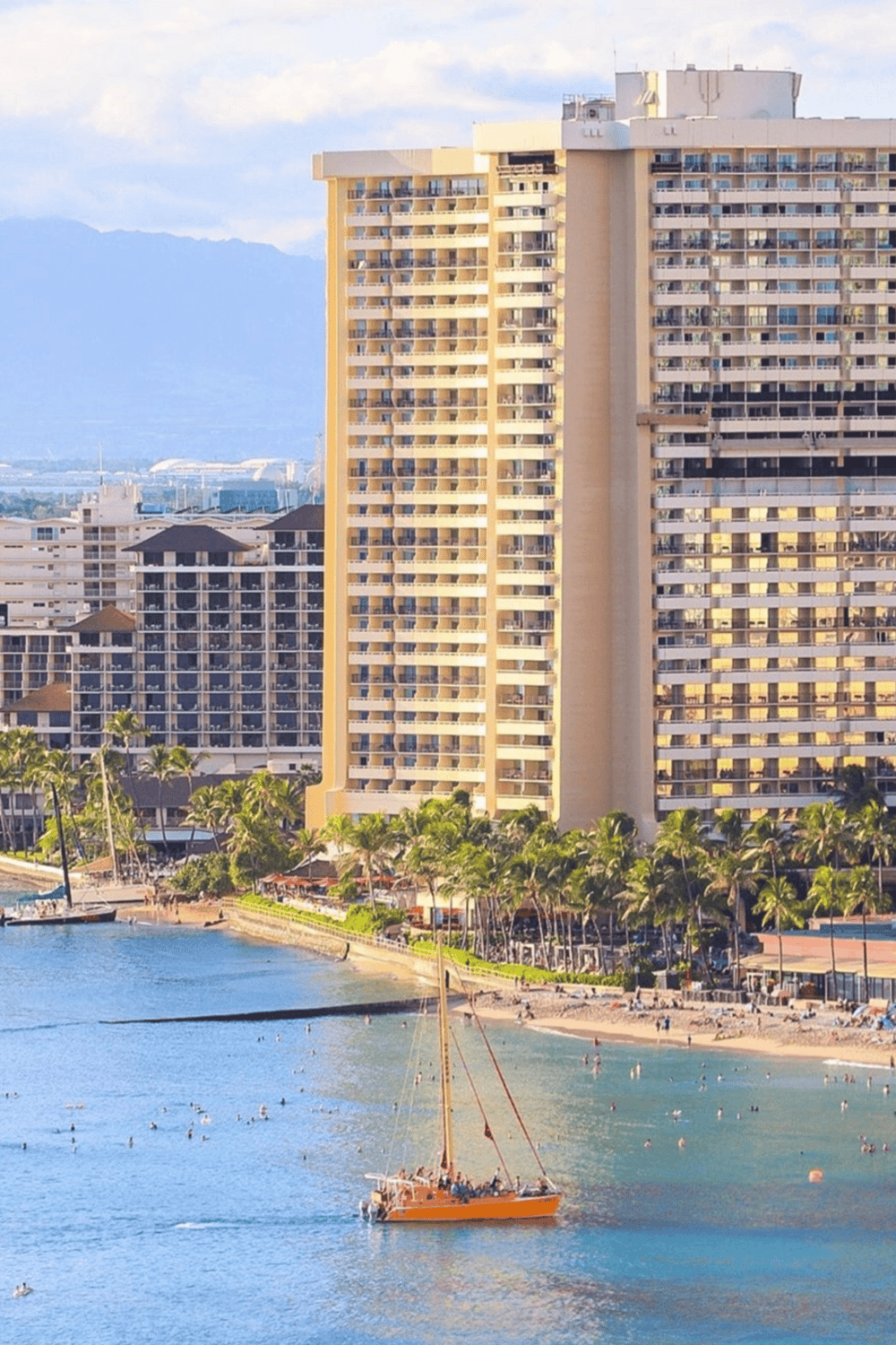 Modern beachfront high-rise hotel in Waikiki, Hawaii, with ocean views and tropical landscaping.