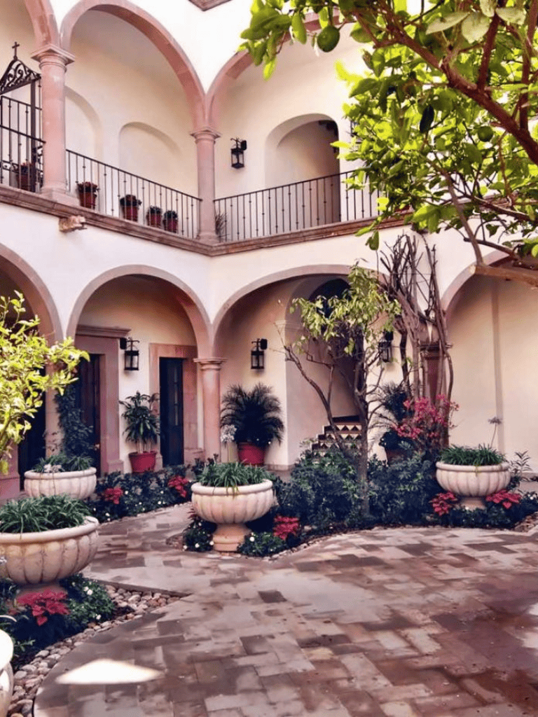 Tranquil courtyard with elegant arches, lush greenery, and classic planter decor for peaceful relaxation.