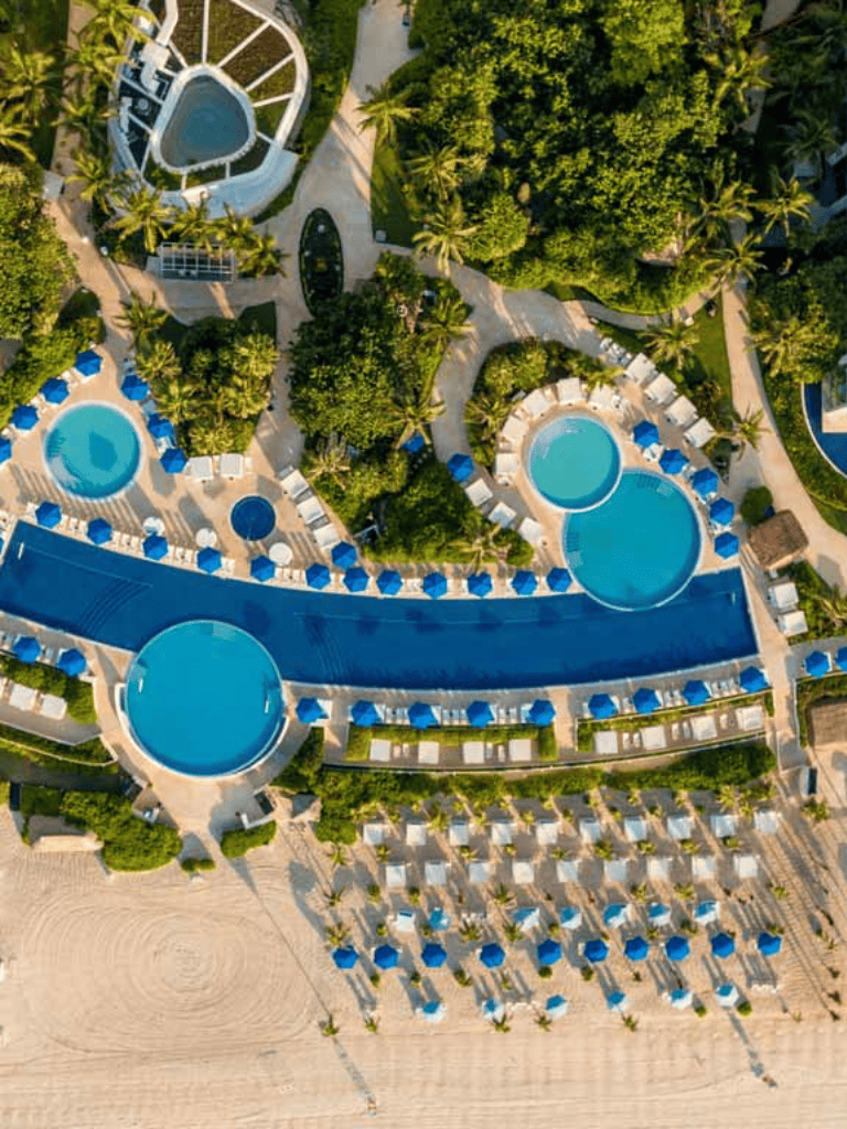Luxurious beachfront resort with multiple pools, lush landscaping, and sunset views, perfect for a tropical vacation.