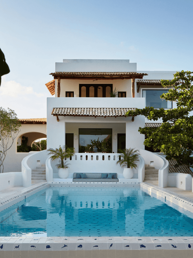 Luxurious white villa with swimming pool, tropical decor, and scenic views.