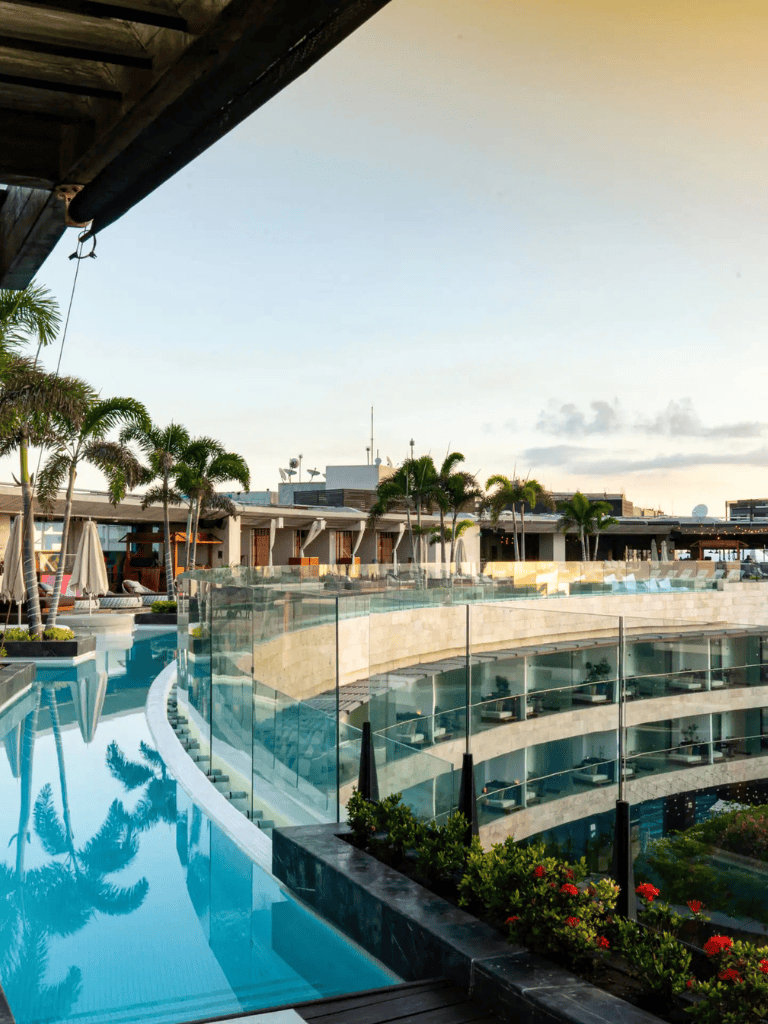 Stunning luxury hotel pool with tropical palm trees at sunset, perfect for relaxing vacation stays.