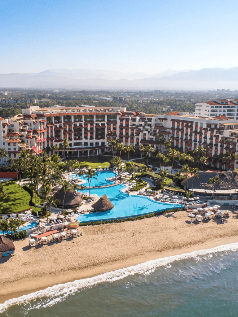 Luxury beachfront resort with swimming pools, palm trees, and ocean view in quest for relaxation and vacation.