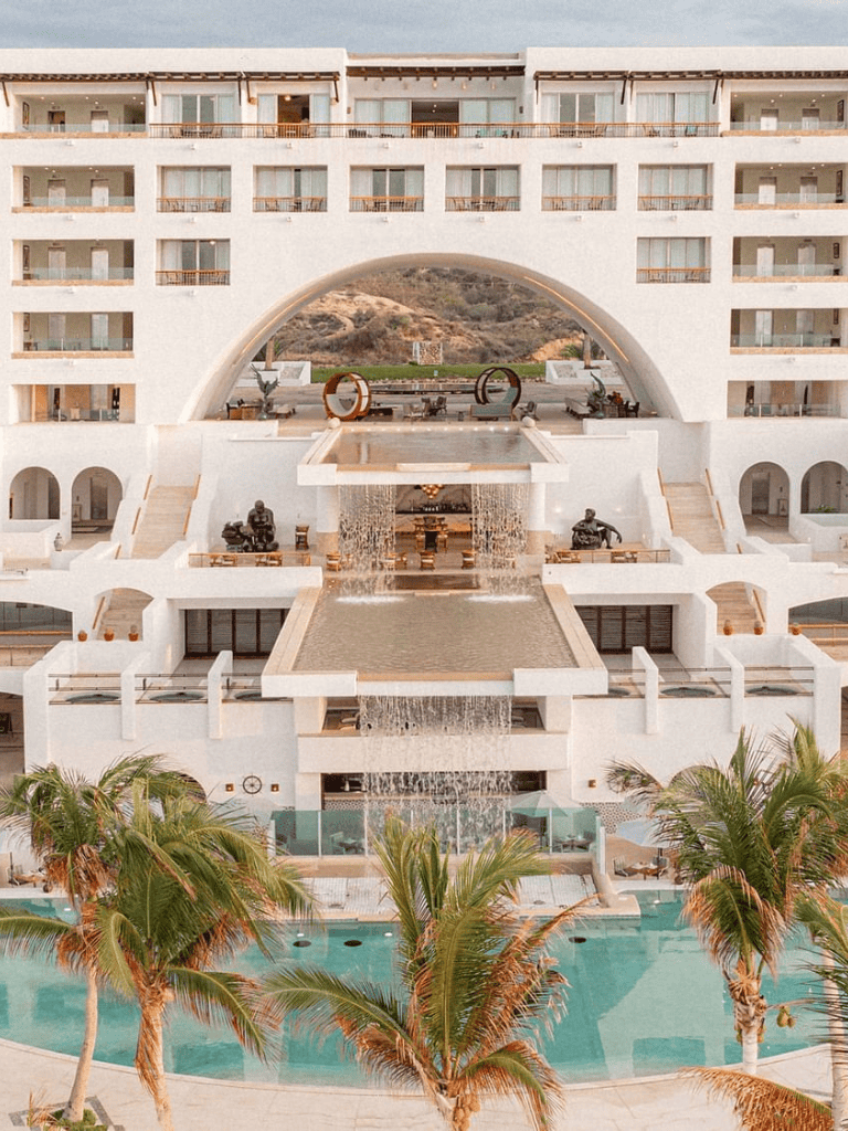 Luxurious beachfront hotel with waterfalls and modern architecture, perfect for relaxation.