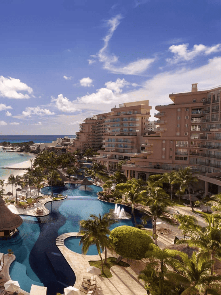 Luxurious beach resort with infinity pool, ocean view, and tropical palm trees.