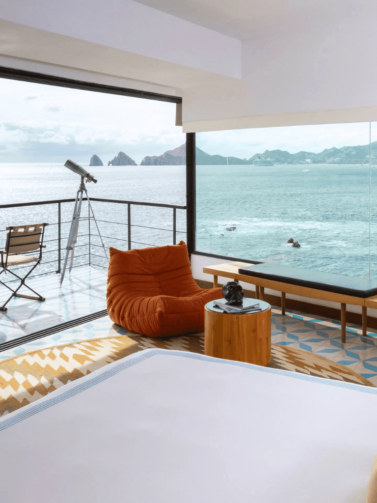 Breathtaking ocean view from a modern hotel room with telescope and comfy seating.