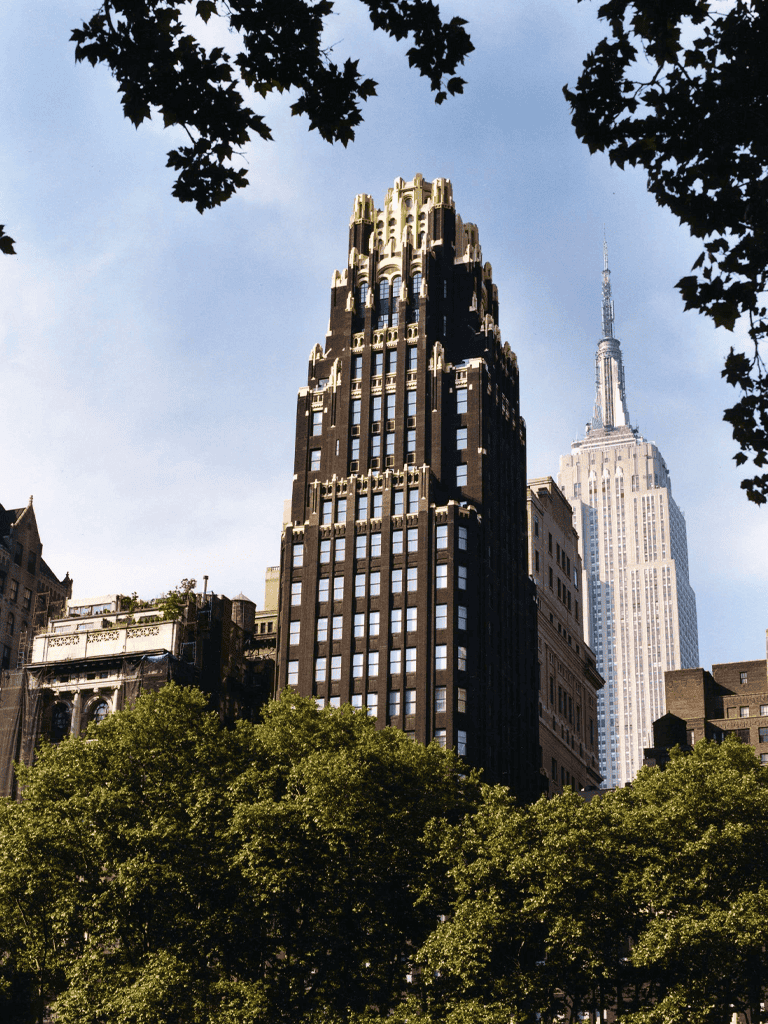 Vintage Art Deco skyscraper in New York City skyline with Empire State Building in background.