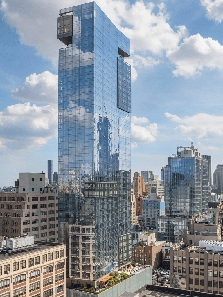 Stunning modern glass skyscraper in downtown city skyline with reflective windows and blue sky.