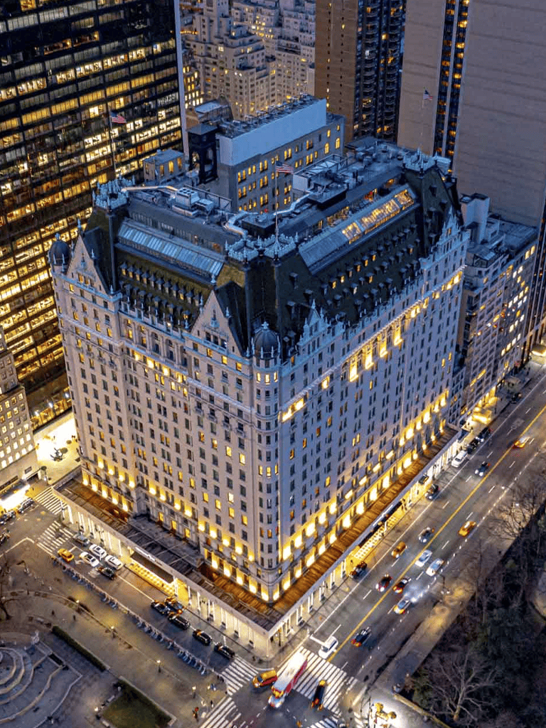Luxurious hotel building at night in New York City with bright exterior lighting.