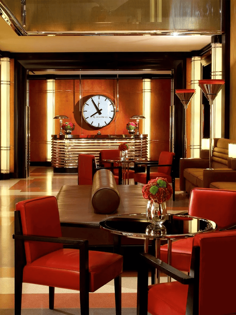 Elegant hotel lobby with modern decor, floral arrangements, and a large wall clock at Chatwal.