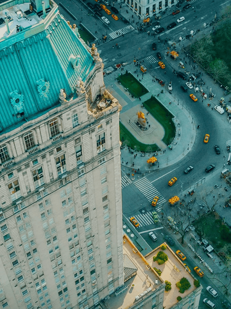Aerial view of city streets with yellow taxis and historic building with blue roof.