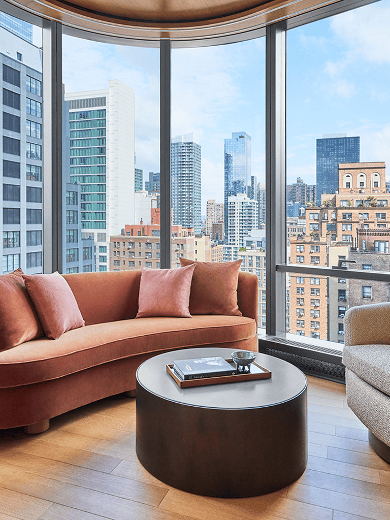 Modern city skyline view from luxury apartment with cozy living room setup.