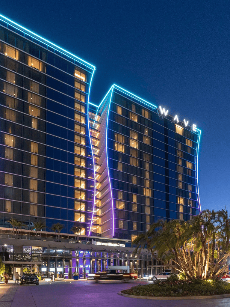 Luxurious oceanfront hotel at night with vibrant neon lighting and modern architecture.