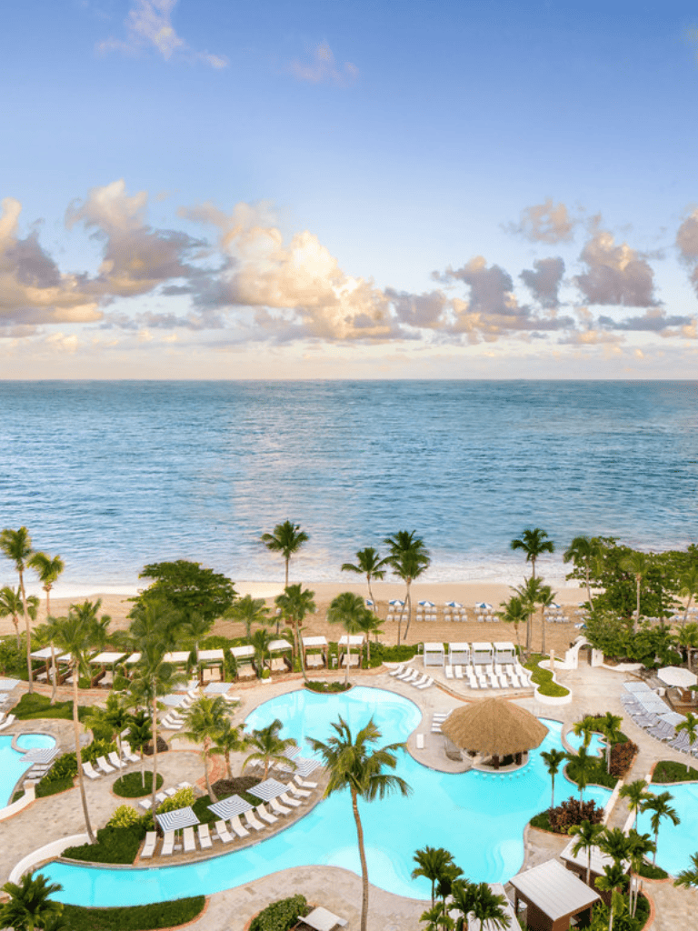 Breathtaking ocean view with swimming pools and palm trees at tropical beach resort.