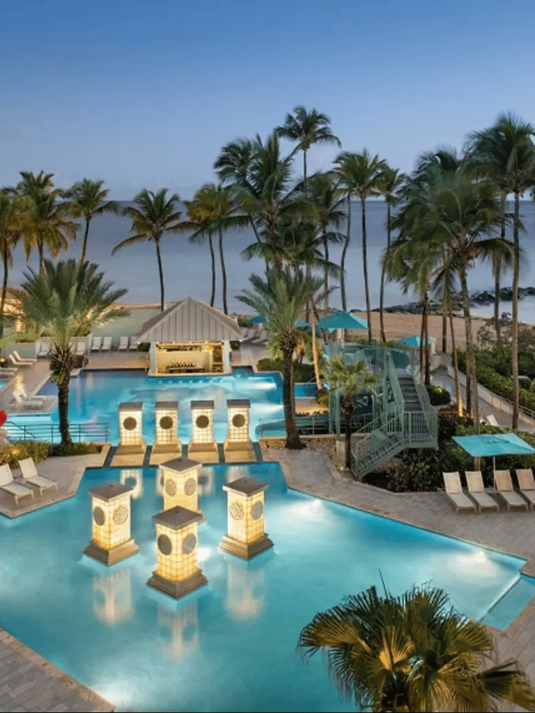 Relaxing tropical beach resort with swimming pool and palm trees at sunset.