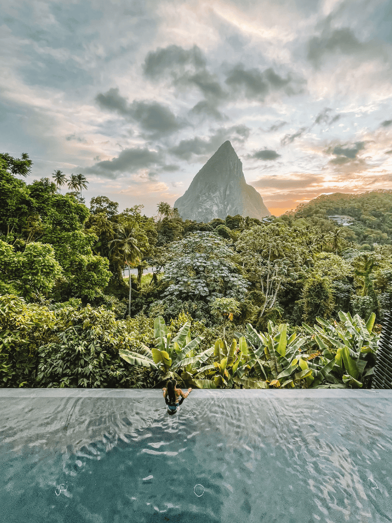 Luxurious infinity pool overlooking lush rainforest and iconic mountain in tropical getaway setting.