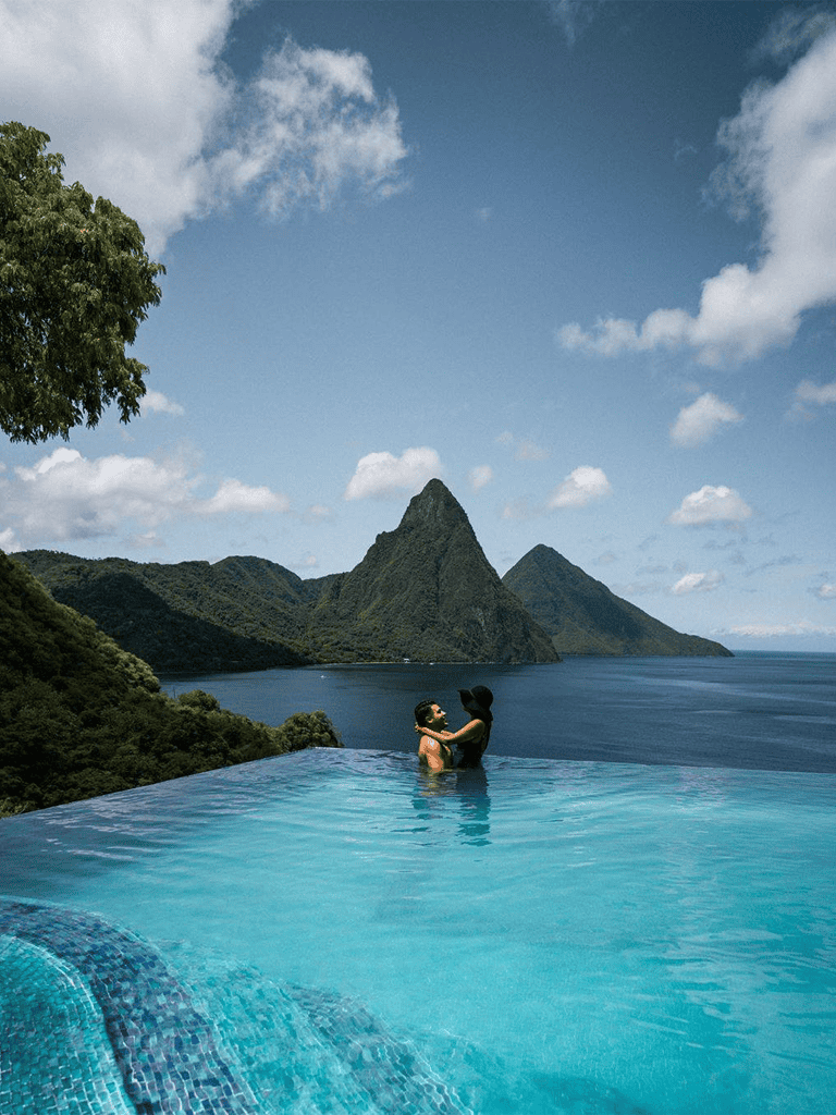 Relaxing couple in infinity pool overlooking lush mountains and ocean landscape in Bora Bora, French Polynesia.