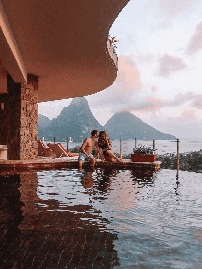 Breathtaking view from luxury infinity pool overlooking mountains and ocean with couple relaxing.