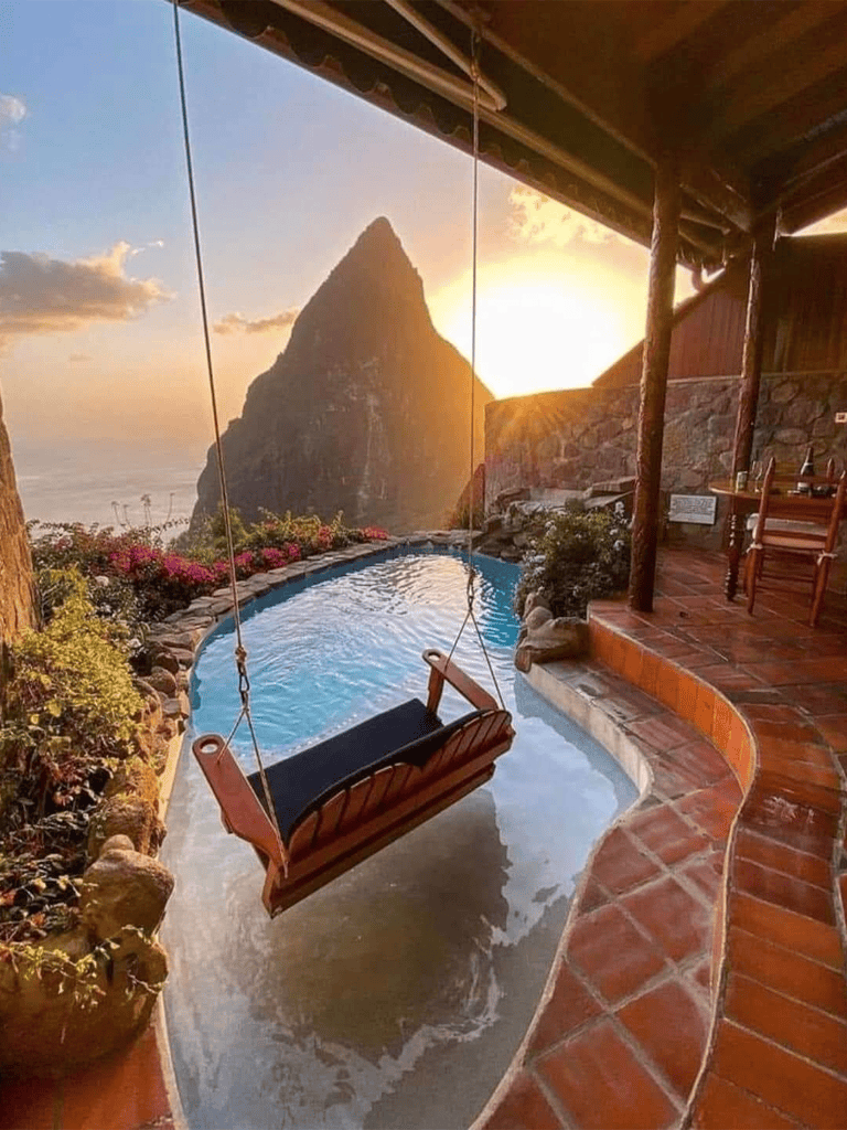Cozy poolside swing overlooking the ocean at sunset with a mountain view in Hawaii.