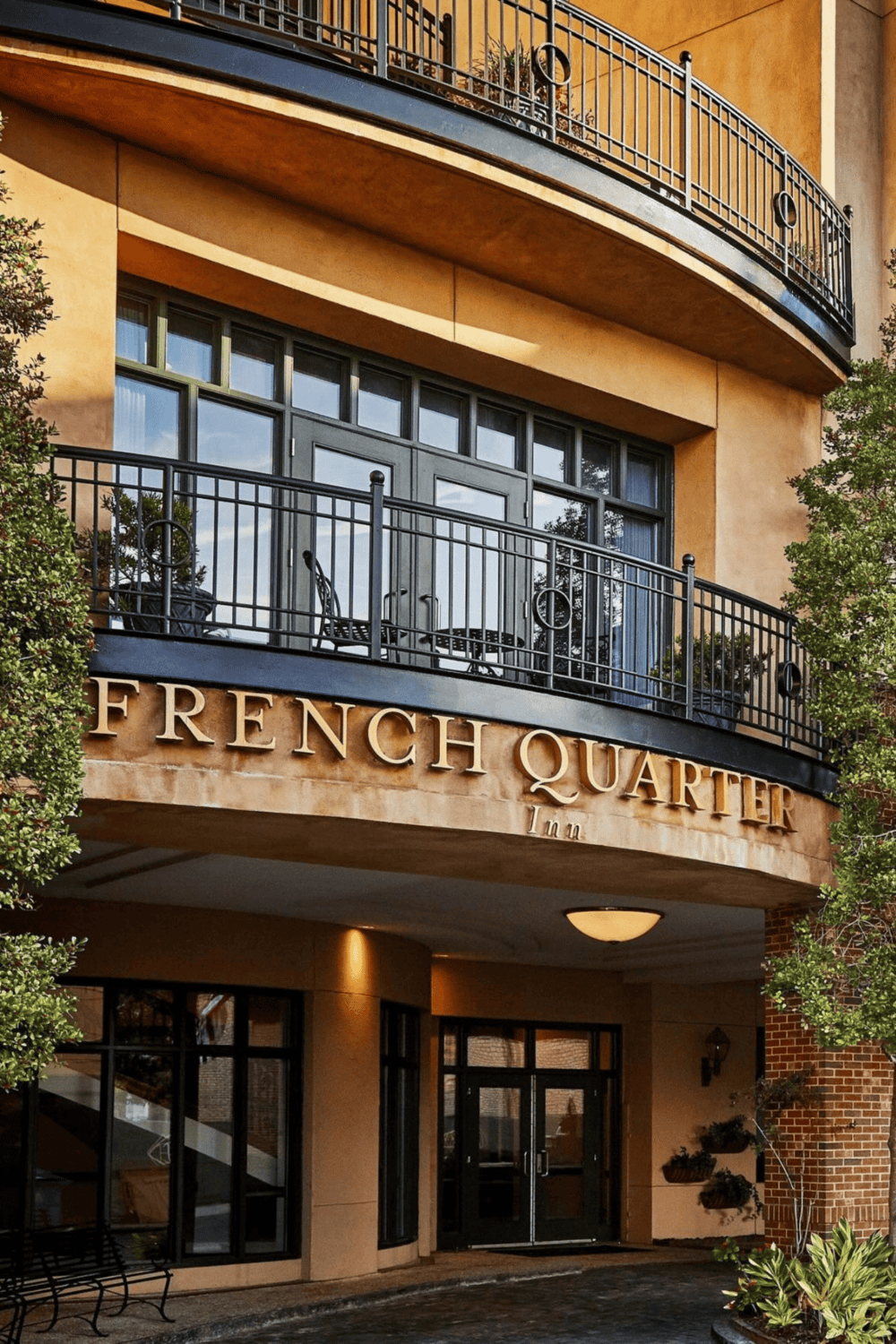 Balcony view of French Quarter Inn with outdoor seating and lush greenery.
