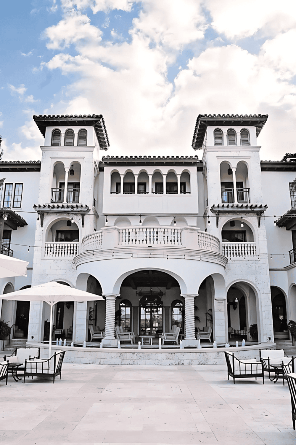 Elegant luxury hotel with Mediterranean architecture and outdoor patio area.
