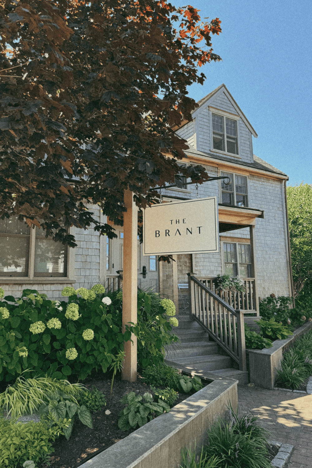 Modern house with garden and "The Brant" sign – expert home and neighborhood guidance.