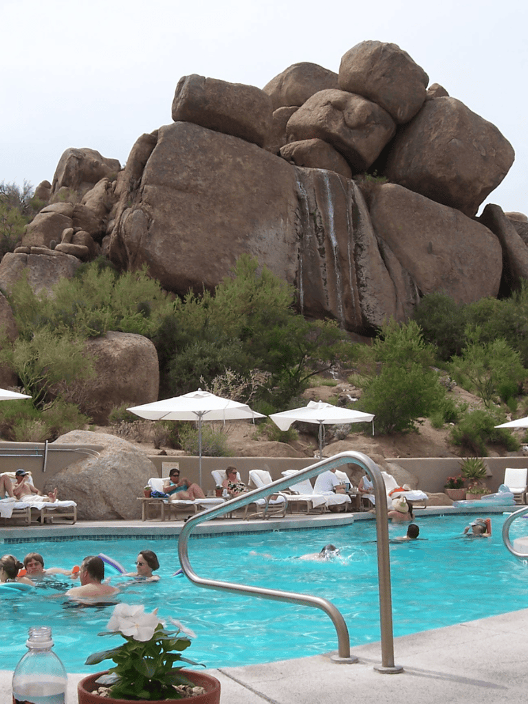 Boulder rocks at Quest for Directions Resort with swimming pool and relaxing area in desert setting.